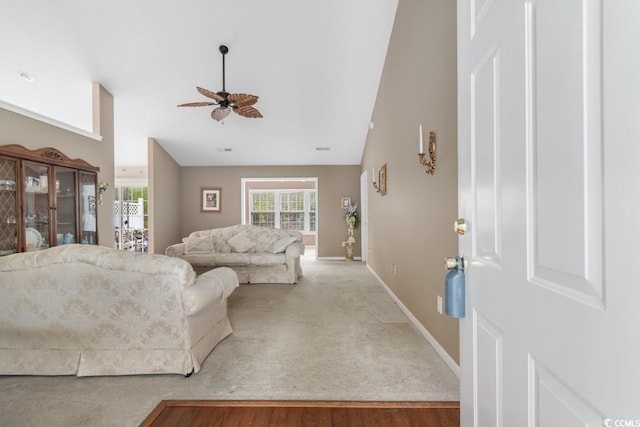 carpeted living area featuring a ceiling fan, high vaulted ceiling, and baseboards