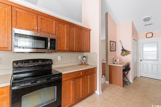 kitchen with stainless steel microwave, brown cabinets, vaulted ceiling, light countertops, and black range with electric cooktop