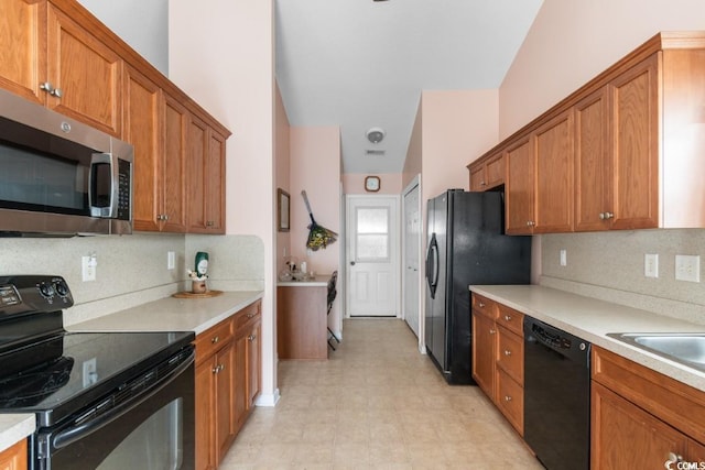 kitchen featuring black appliances, brown cabinets, light countertops, and light floors