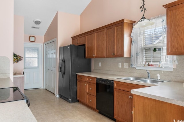 kitchen featuring brown cabinetry, decorative light fixtures, light countertops, black appliances, and a sink