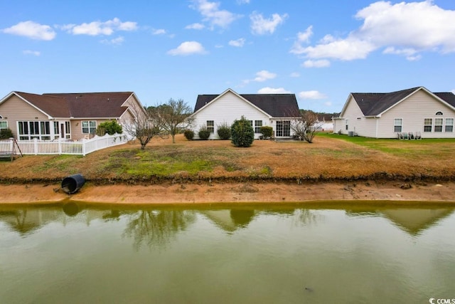 back of property featuring a water view and fence