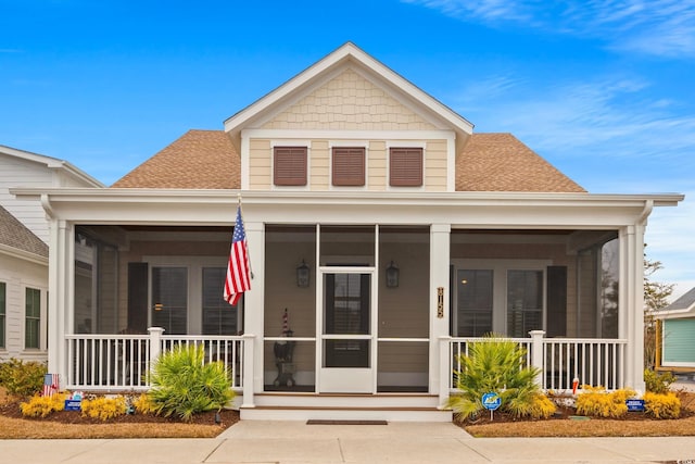 view of front of house featuring covered porch, a sunroom, and a shingled roof