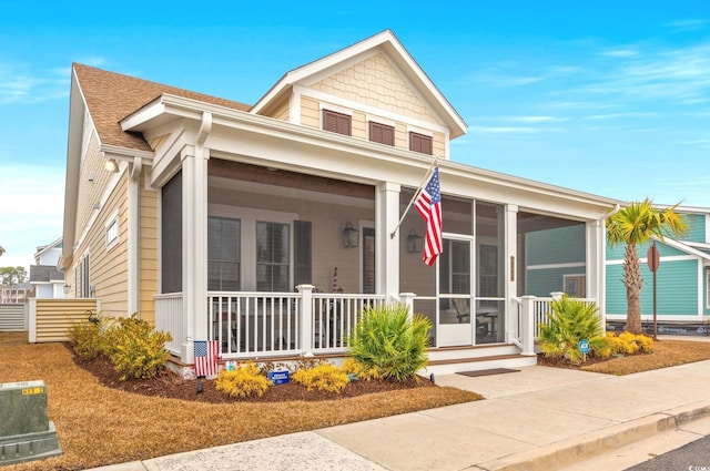 view of front of house featuring a porch, a sunroom, and roof with shingles