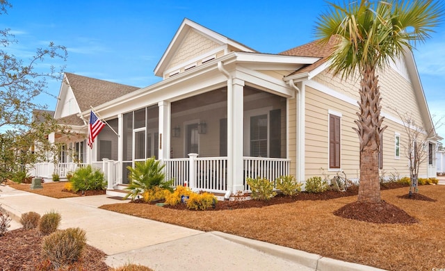 view of front of property with a porch, a shingled roof, and a sunroom