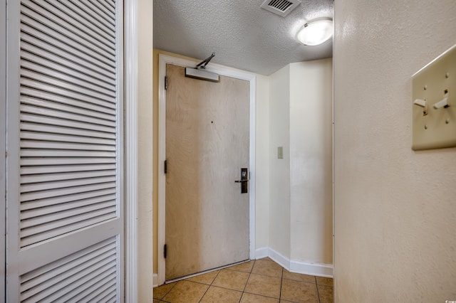 corridor featuring a textured ceiling and light tile patterned flooring