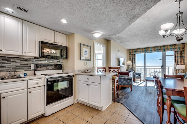 kitchen with white cabinetry, kitchen peninsula, white range with electric stovetop, and decorative light fixtures