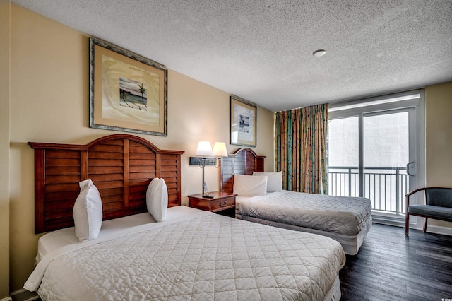 bedroom with access to exterior, dark hardwood / wood-style floors, and a textured ceiling