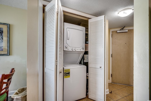 laundry room with stacked washer / drying machine, a textured ceiling, and light tile patterned floors