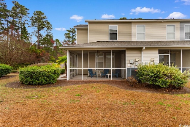 rear view of property featuring a patio, a lawn, and a sunroom