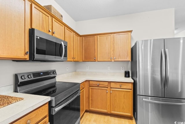 kitchen featuring appliances with stainless steel finishes and light hardwood / wood-style flooring