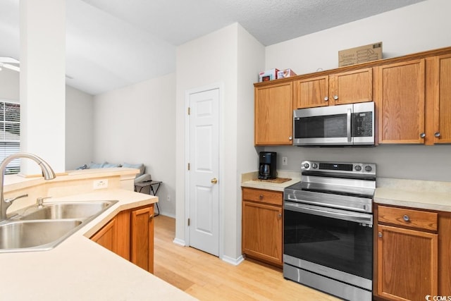 kitchen featuring sink, appliances with stainless steel finishes, a textured ceiling, and light hardwood / wood-style flooring