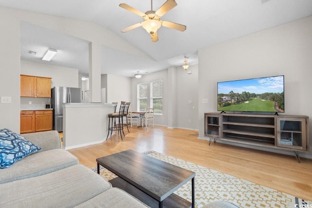 living room with ceiling fan, light hardwood / wood-style flooring, and lofted ceiling