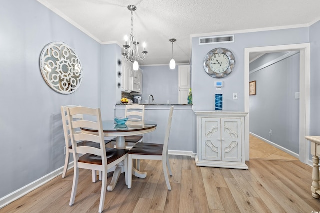 dining room with light wood-style floors, visible vents, and crown molding