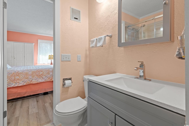 ensuite bathroom with visible vents, a textured wall, toilet, a textured ceiling, and wood finished floors