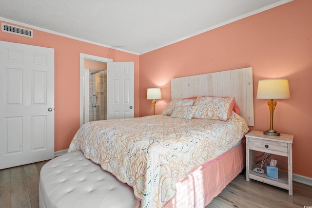 bedroom with wood finished floors, visible vents, and baseboards