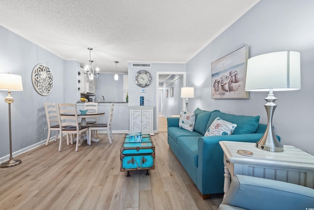 living room featuring a textured ceiling, visible vents, baseboards, ornamental molding, and light wood-type flooring