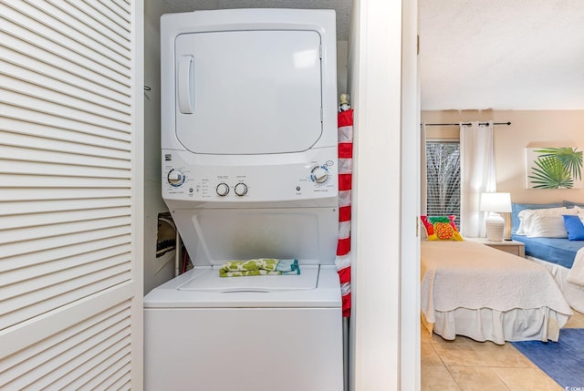 washroom featuring stacked washing maching and dryer and light tile patterned floors