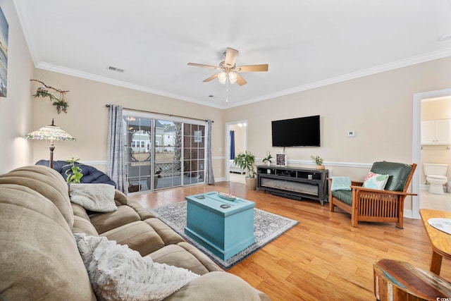 living area with visible vents, ornamental molding, and wood finished floors