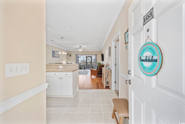 foyer entrance with light tile patterned flooring, ornamental molding, and ceiling fan