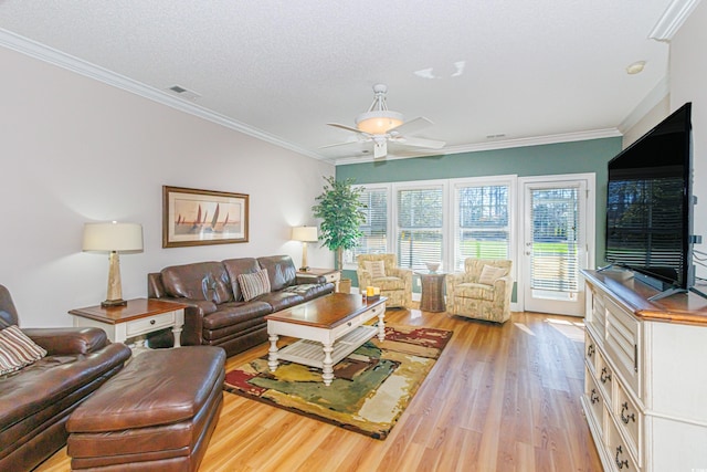 living room with light wood-style flooring, visible vents, ceiling fan, and ornamental molding