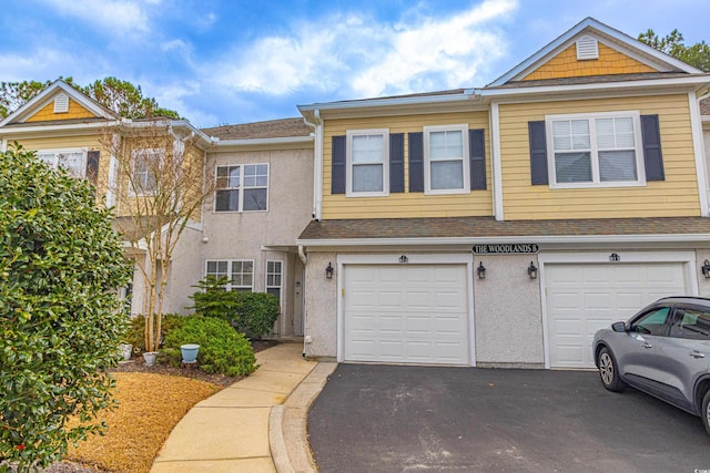 view of property featuring driveway, a shingled roof, an attached garage, and stucco siding