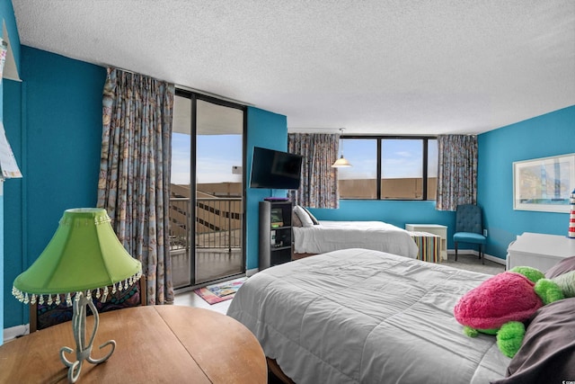 bedroom with access to outside, expansive windows, and a textured ceiling