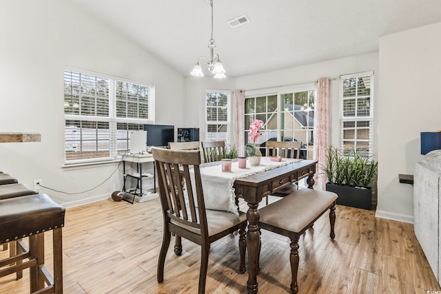 dining room with an inviting chandelier, vaulted ceiling, and light hardwood / wood-style flooring