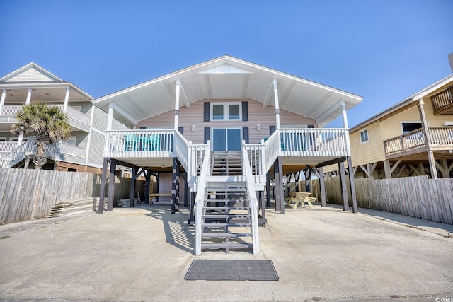 rear view of house featuring stairs, a carport, fence, and a patio area