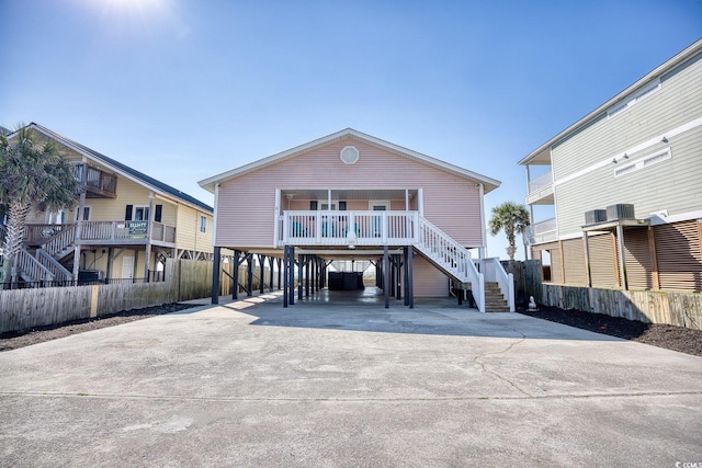 coastal home featuring stairs, a carport, fence, and driveway