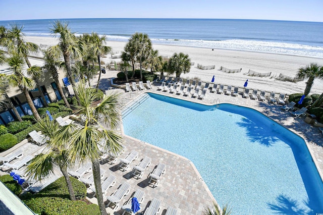 pool featuring a water view, a view of the beach, and a patio