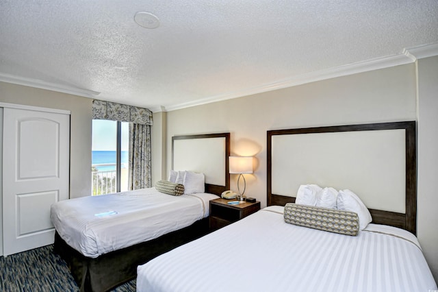 bedroom featuring a water view, crown molding, and a textured ceiling