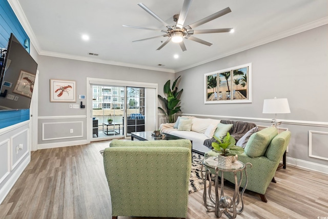 living room with light hardwood / wood-style flooring, ornamental molding, and ceiling fan