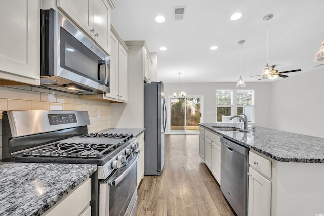 kitchen featuring white cabinetry, stainless steel appliances, sink, and a center island with sink