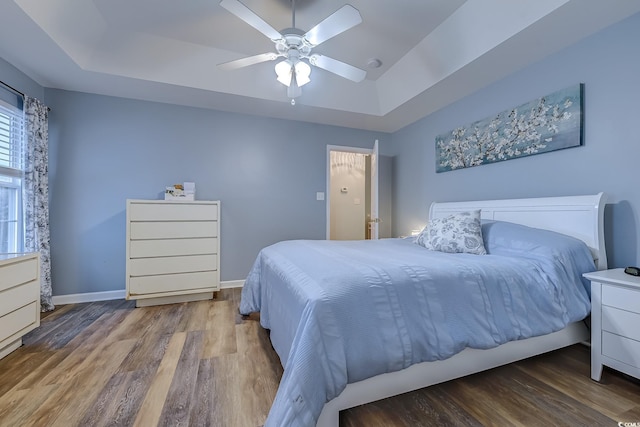 bedroom featuring a tray ceiling, ceiling fan, and hardwood / wood-style flooring