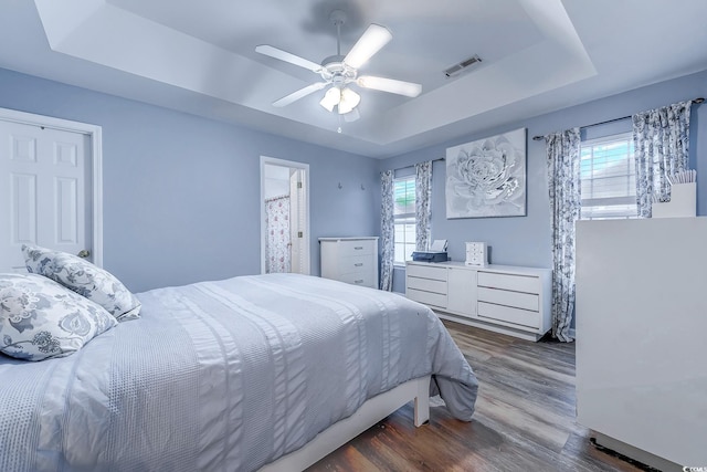 bedroom featuring a raised ceiling, dark hardwood / wood-style floors, and ceiling fan