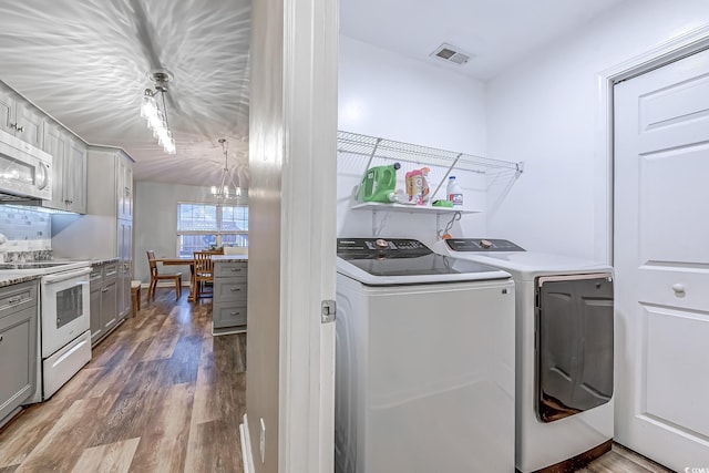 laundry area featuring washing machine and dryer, hardwood / wood-style floors, and a chandelier