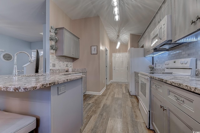 kitchen with sink, light hardwood / wood-style flooring, gray cabinets, white appliances, and backsplash