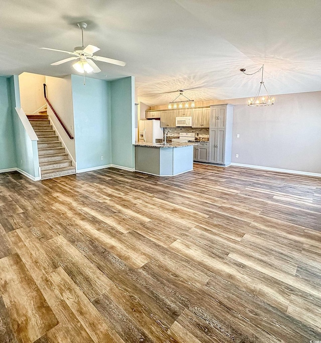 920 Leather Leaf Ln, Longs, SC 29568 - unfurnished living room with wood finished floors, baseboards, ceiling fan, stairs, and a chandelier