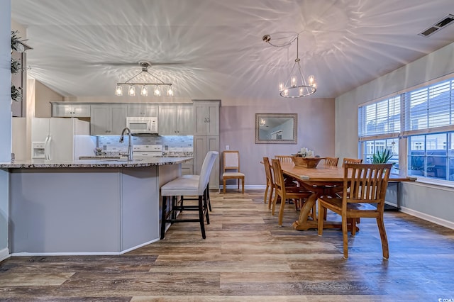 dining area featuring an inviting chandelier, sink, and dark hardwood / wood-style floors