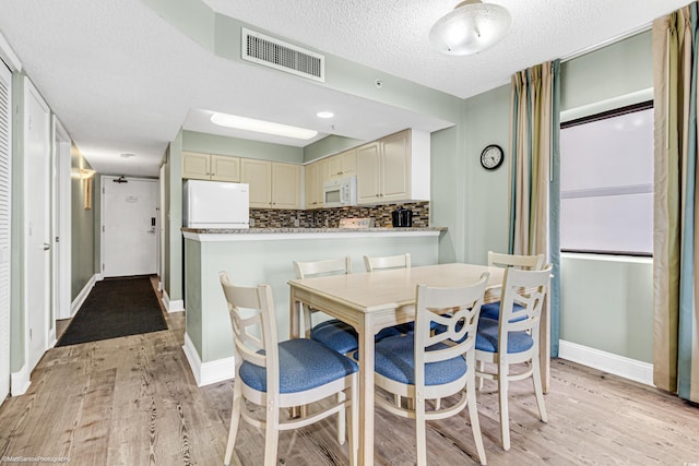 kitchen featuring backsplash, white appliances, light hardwood / wood-style flooring, and cream cabinetry