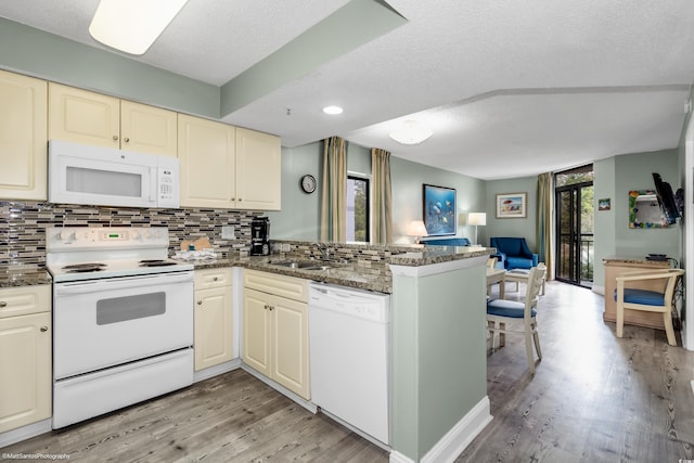 kitchen featuring sink, dark stone countertops, kitchen peninsula, white appliances, and decorative backsplash