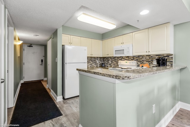 kitchen with white appliances, kitchen peninsula, and light hardwood / wood-style flooring