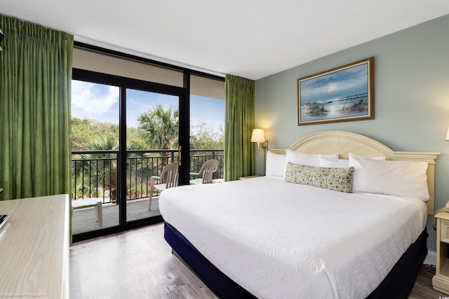 bedroom featuring hardwood / wood-style flooring, a wall of windows, and access to outside