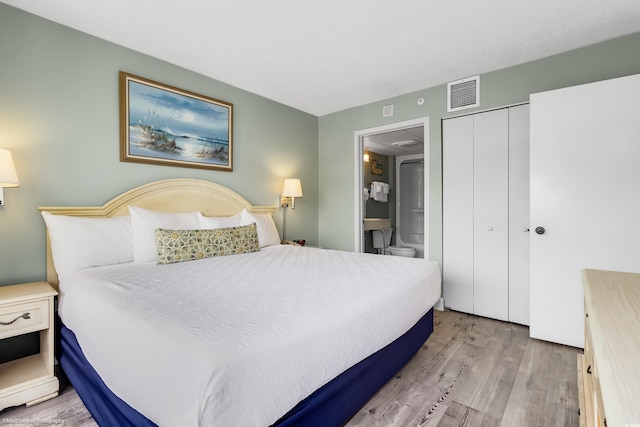 bedroom featuring ensuite bathroom, light wood-type flooring, and a closet