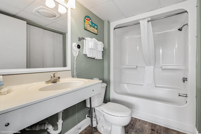 full bathroom with sink, hardwood / wood-style flooring, a paneled ceiling, shower / bath combination, and toilet