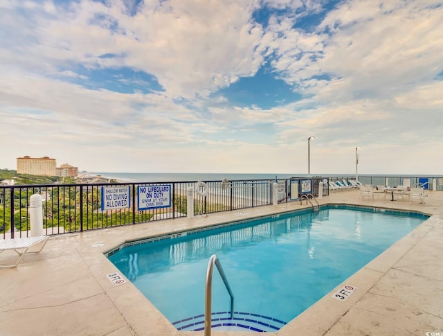 view of swimming pool with a patio and a water view