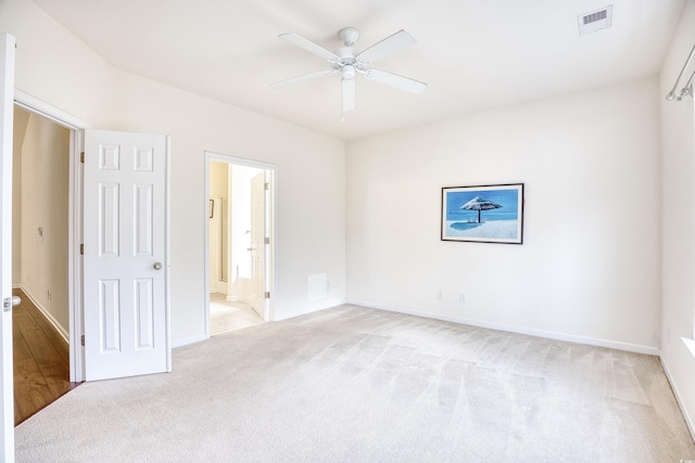 empty room with light carpet, baseboards, visible vents, and a ceiling fan