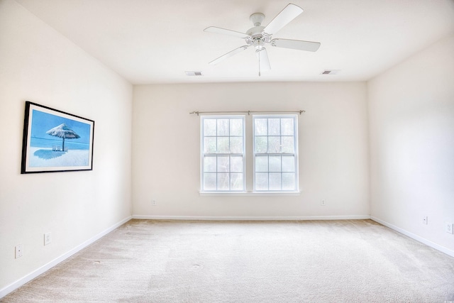 empty room featuring light colored carpet, visible vents, ceiling fan, and baseboards