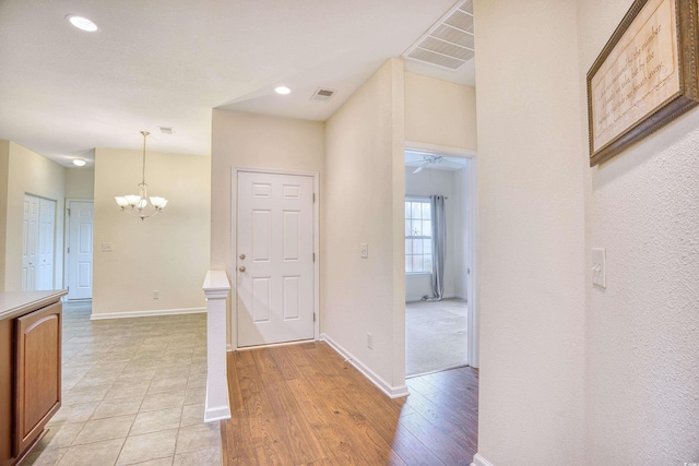 foyer with light wood-style flooring, visible vents, and baseboards