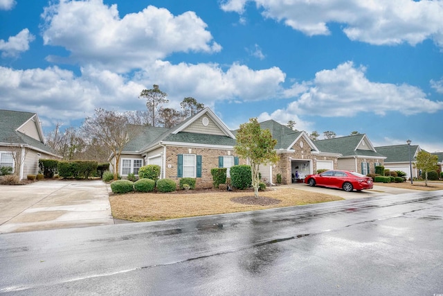 view of front of home featuring a residential view, brick siding, driveway, and an attached garage